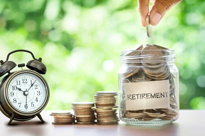 Manually placing coins in a jar with the inscription Pension next to the clock