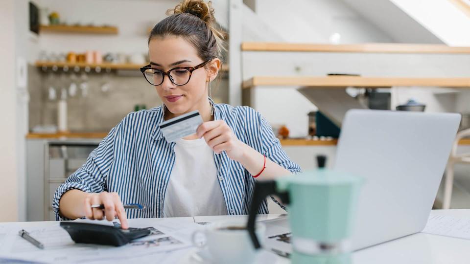 A young woman pays bills / buys online with a credit card.