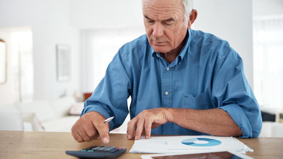 an older man using a calculator while reviewing his budget