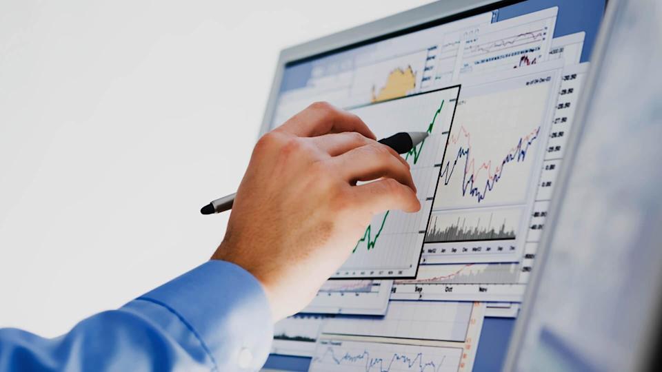 A businessman researching stock market data on a computer monitor.