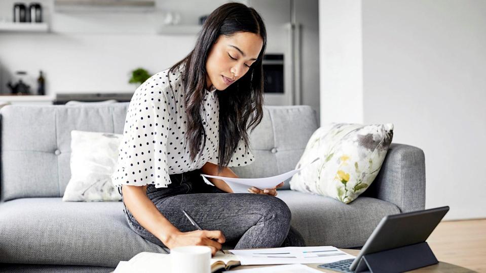 A young woman analyzing bills while writing in a diary.