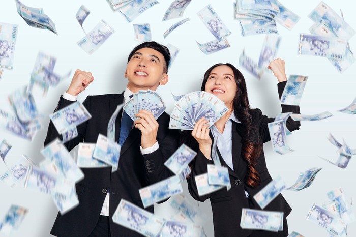 Two people in business suits with money flying around. 