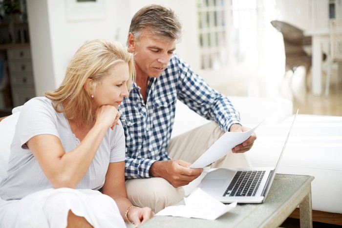 Two people behind a laptop, looking at documents