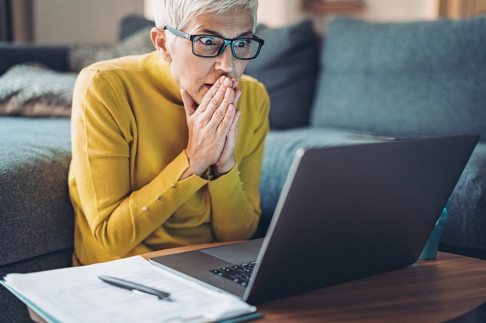 A mature person stares at the computer screen in shock