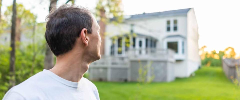 A young man, the owner of a house in Herndon, Northern Virginia, a Fairfax county residence, overlooks the backyard in the spring or summer