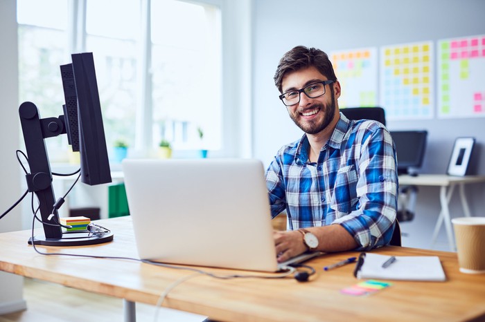 A smiling person behind a laptop